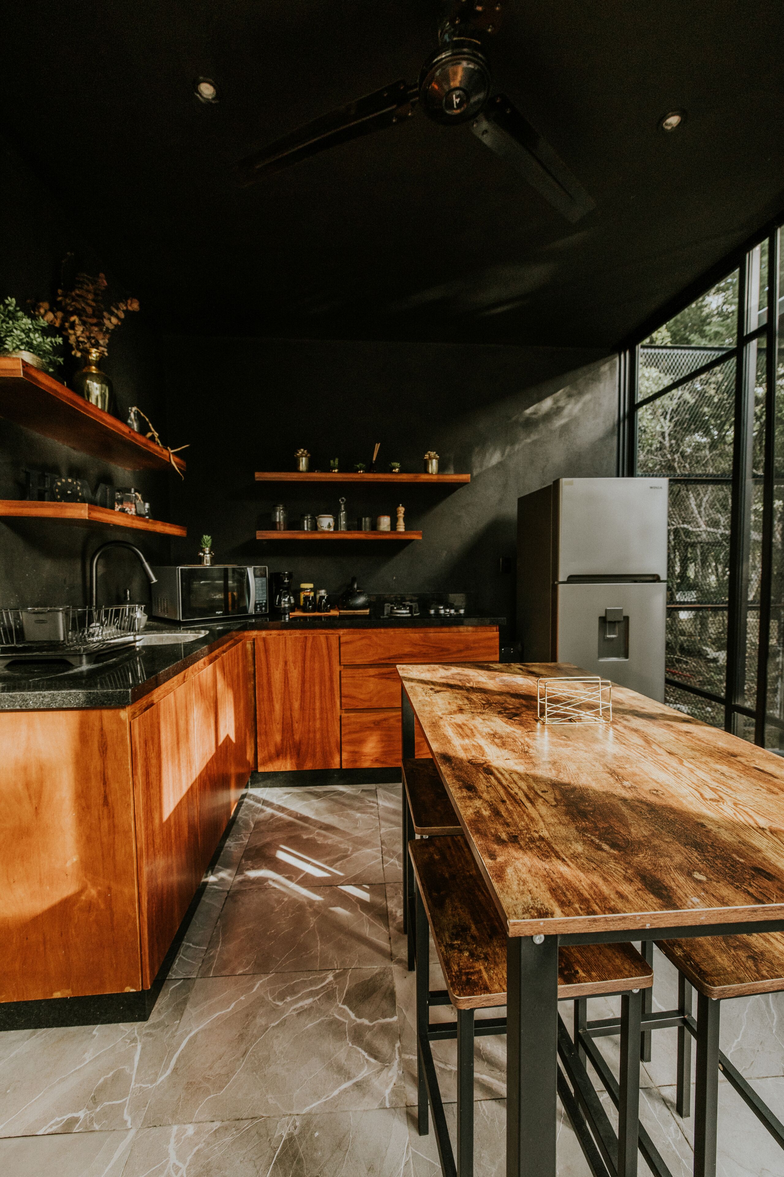 A modern kitchen with wooden cabinetry, a marble countertop, and a built-in refrigerator.