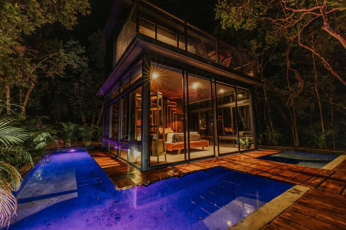 A modern house with a glass facade, a pool, and a wooden deck.