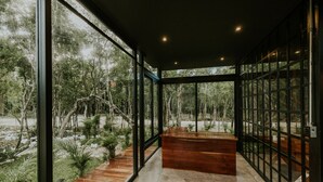 Un intérieur moderne avec de grandes fenêtres, un banc en bois et un sol en pierre.