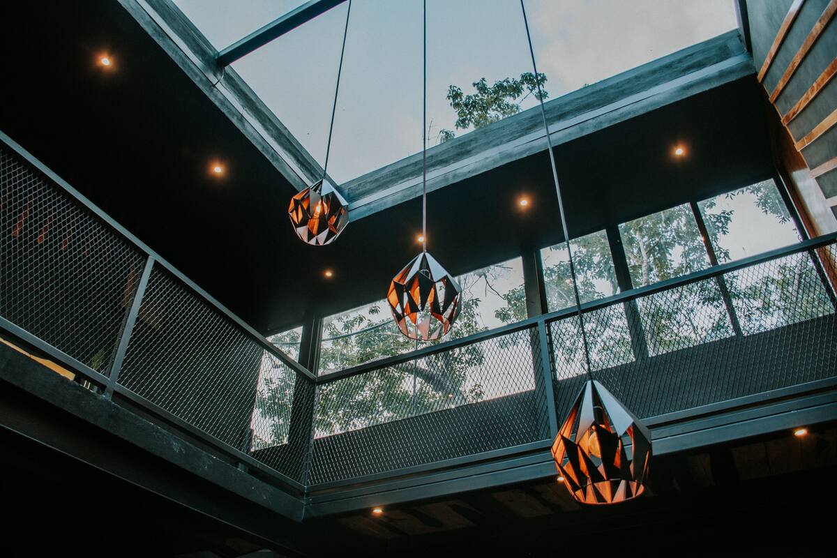 A modern interior with geometric hanging lights and large windows.