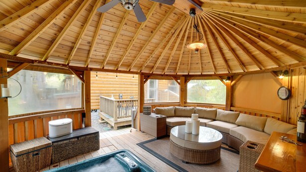 A wooden cabin interior with a hot tub, a sofa, and a dining area. - 'Moose Lodge' Cabin w/ Entertainment Gazebo! (Baring)