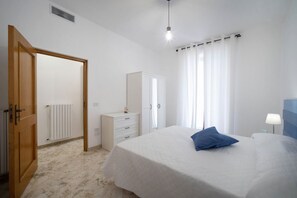 Een slaapkamer met een bed, een kastje, een garderobe en een radiator.