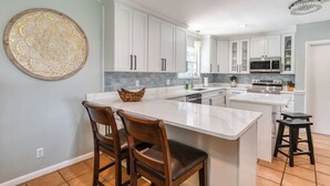 Una cocina moderna con armarios blancos, una isla de mármol y un gran adorno mural.