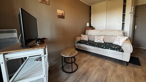 Huoneessa on sänky, tietokoneella varustettu työpöytä, pieni pyöreä pöytä ja sohva.
