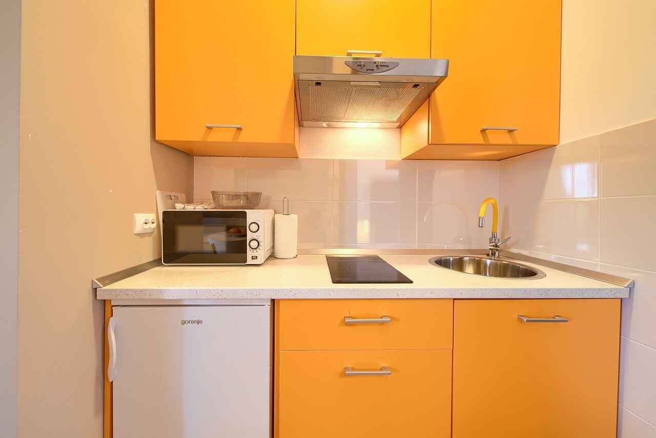 A compact kitchen with a microwave, toaster, and sink.