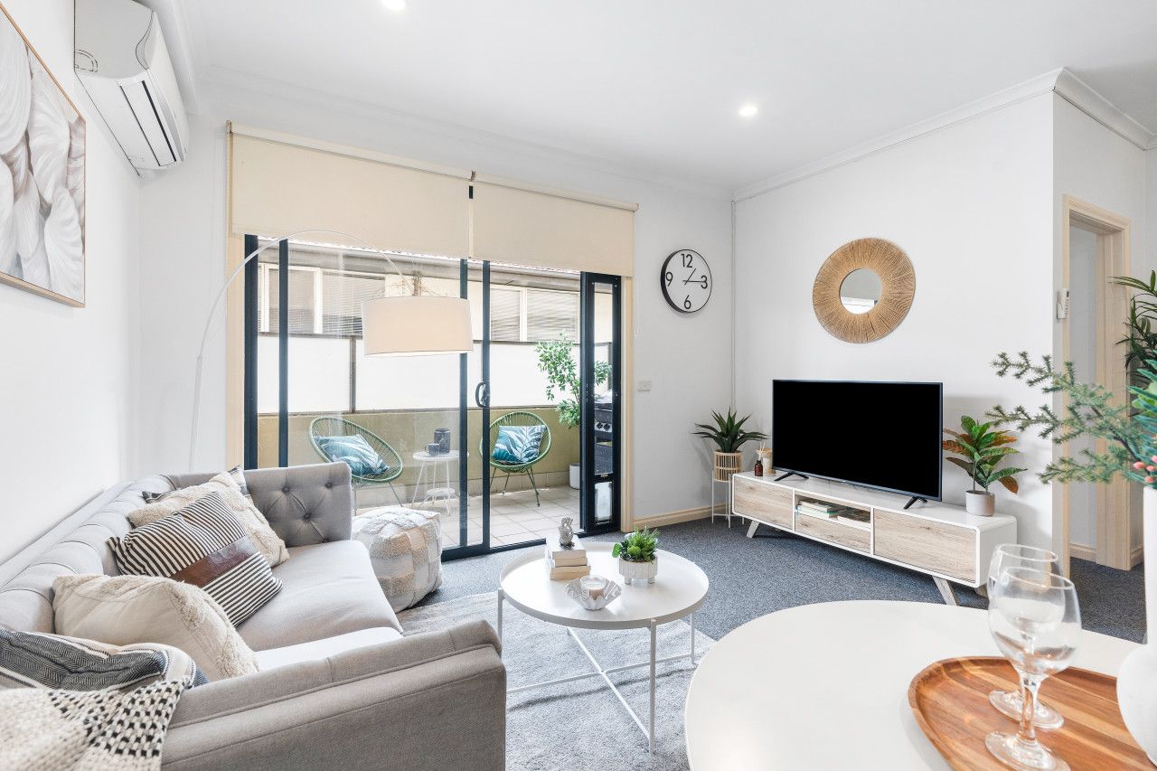 A modern living room with a sofa, coffee table, TV, and a balcony with sliding doors.