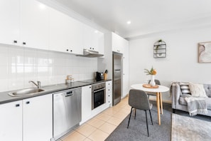 A modern kitchen with white cabinets, stainless steel appliances, and a grey countertop.