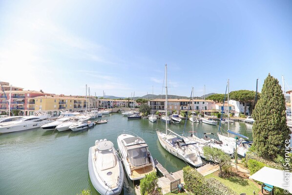 A marina with various boats docked, surrounded by buildings and greenery.
