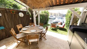 A covered patio with a round wooden table set for dining, surrounded by wooden chairs. - Nice 4 bedroom house with mooring (PORT GRIMAUD)