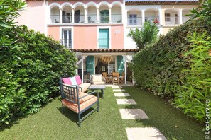 Une cour avec un espace aménagé pour s’asseoir, un patio couvert et un bâtiment doté de balcons.