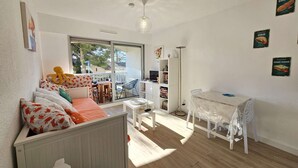 Une pièce lumineuse comprenant un lit, une petite table, une chaise, une bibliothèque et une table à manger.
