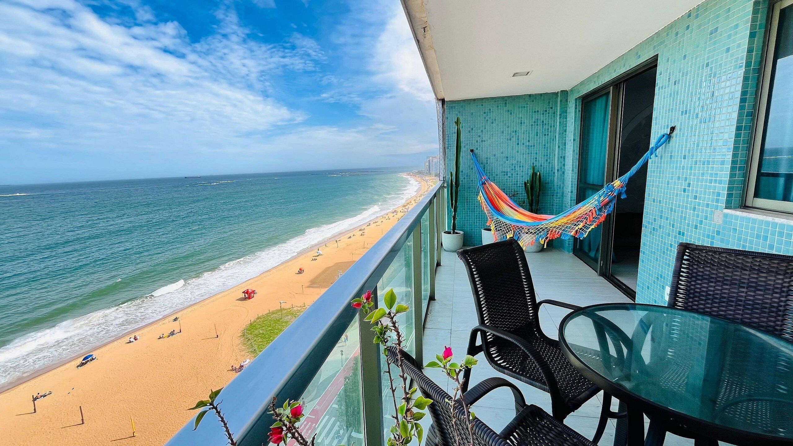 Ein Balkon mit Blick auf Strand und Meer, eine Hängematte und Gartenmöbel.