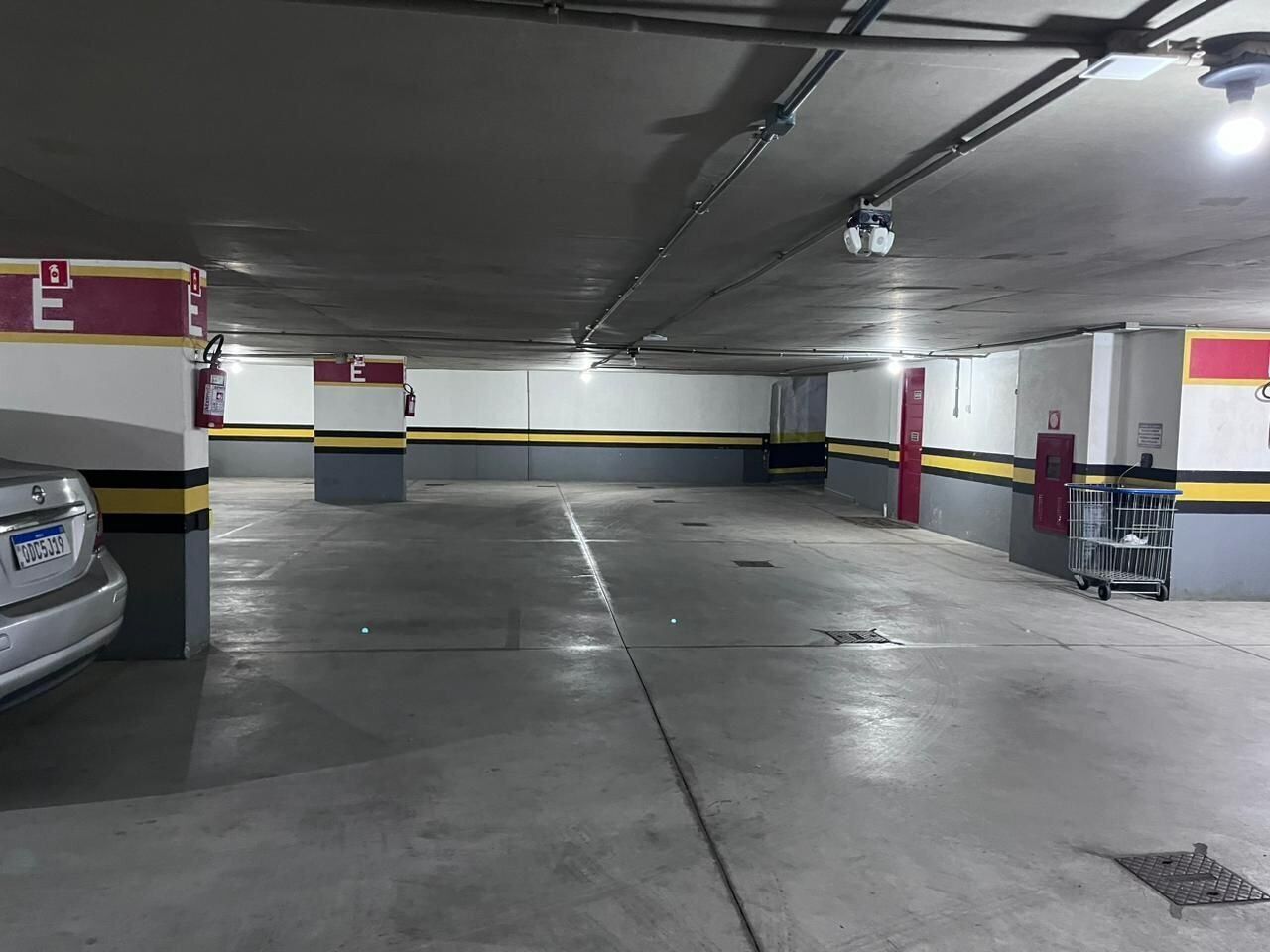 Ett parkeringsgarage med betonggolv, gul- och svartrandiga väggar och en bil parkerad på vänster sida.