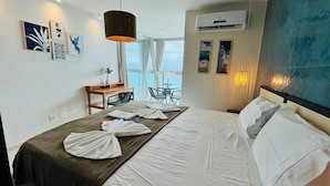 Ett hotellrum med en säng, ett skrivbord, en stol, ett bord och konstverk på väggarna.
