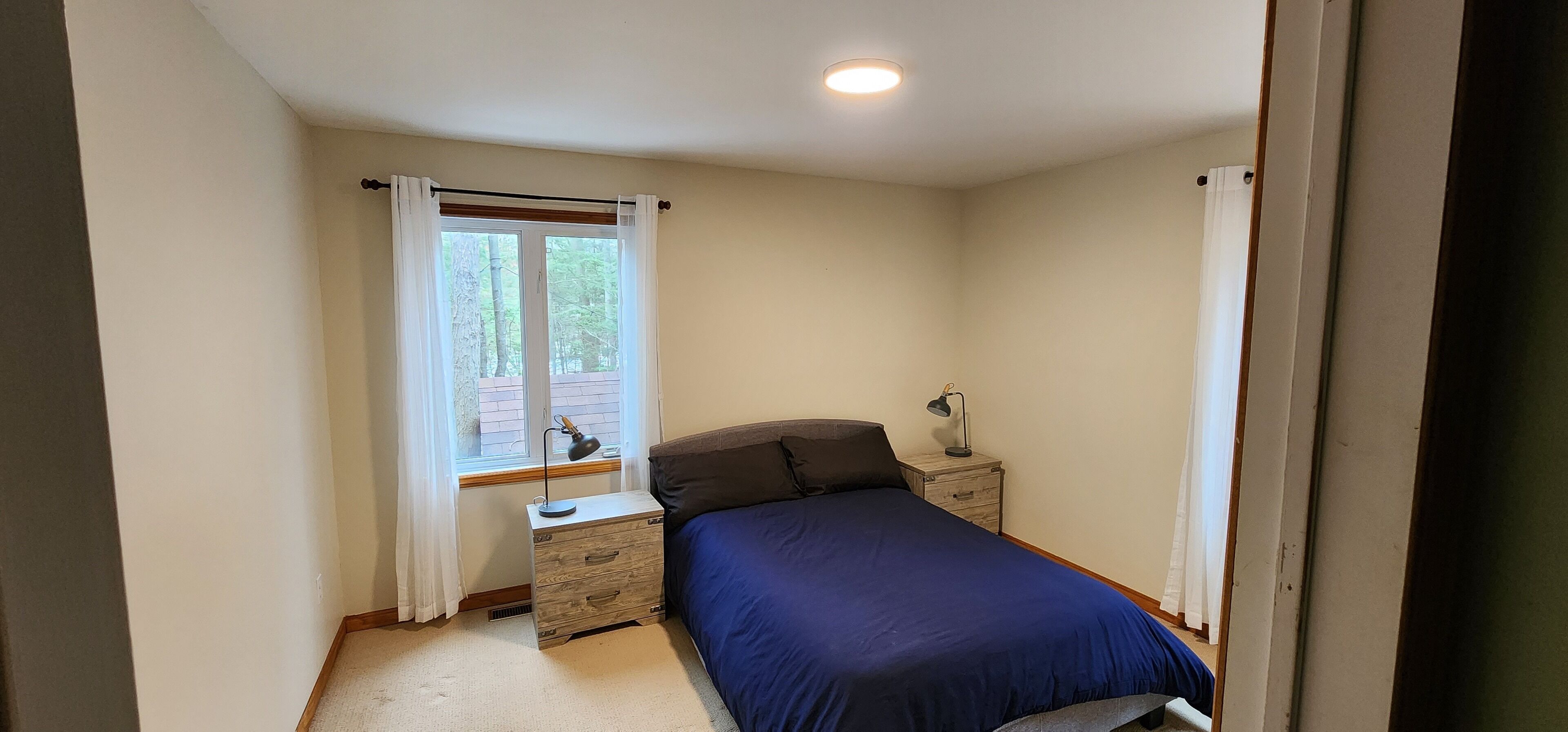 Una camera da letto con un letto singolo, un comodino, una lampada e una finestra con tende.