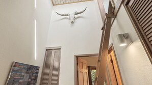 Un techo alto con decoración de cráneo de toro, contraventanas de madera y un cuadro con montañas.
