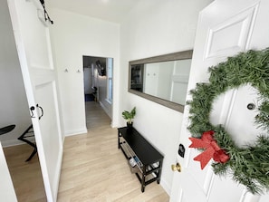 Enter a welcoming space with a festive touch, featuring a cozy bench and a potted plant.