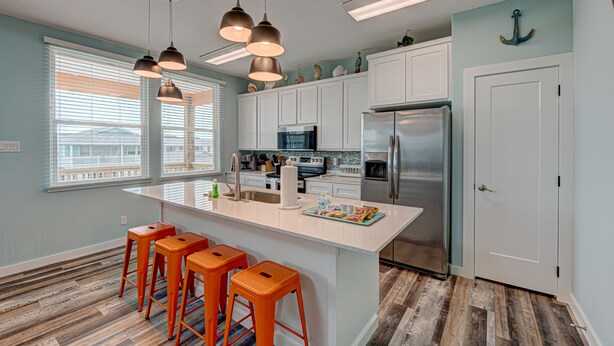 A modern kitchen with white cabinets, stainless steel appliances, and a large island with bar stools.