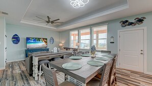 A spacious kitchen with a large island, a ceiling fan, and a dining area with a wooden table and chairs.