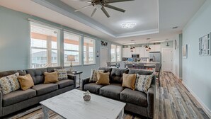A spacious living room with a grey sofa set, a white coffee table, and a ceiling fan.