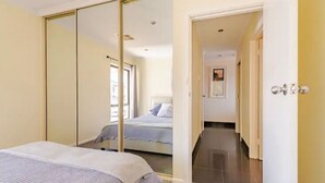 A bedroom with a bed, a wardrobe, and a hallway leading to another room. - Luxurious beachfront, panoramic views (West Lakes Shore)