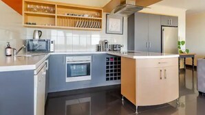 A modern kitchen with grey cabinets, a built-in oven, and a wine rack. - Luxurious beachfront, panoramic views (West Lakes Shore)