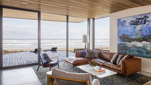 A modern living room with a leather sofa, a coffee table, and a large painting. - Luxury Designer Beachfront Home 3 Bed, 3.5 Bath in Arch Cape, Oregon. (Arch Cape)