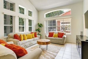 A spacious living room with two sofas, a coffee table, and large windows.