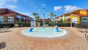 A courtyard with a central water feature, surrounded by multi-story buildings with balconies and a brick floor.