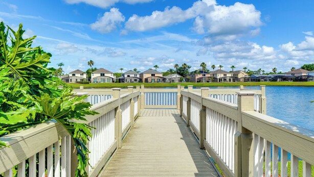 A wooden boardwalk leading to a row of houses by a lake.