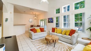 A spacious living area with two white sofas, a wooden coffee table, and a ceiling fan.