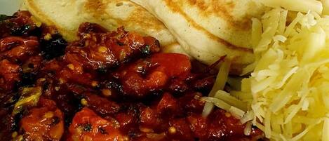 A plate with pancakes, a tomato-based dish, and shredded cheese.