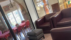 A room with leather sofas, a small ottoman, and a glass partition. - St Ann's Guest House Ltd. (Port of Spain)
