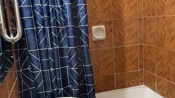 Un baño con un lavamanos blanco, una ducha con un patrón de espiga en madera y una cortina azul con diseño geométrico.