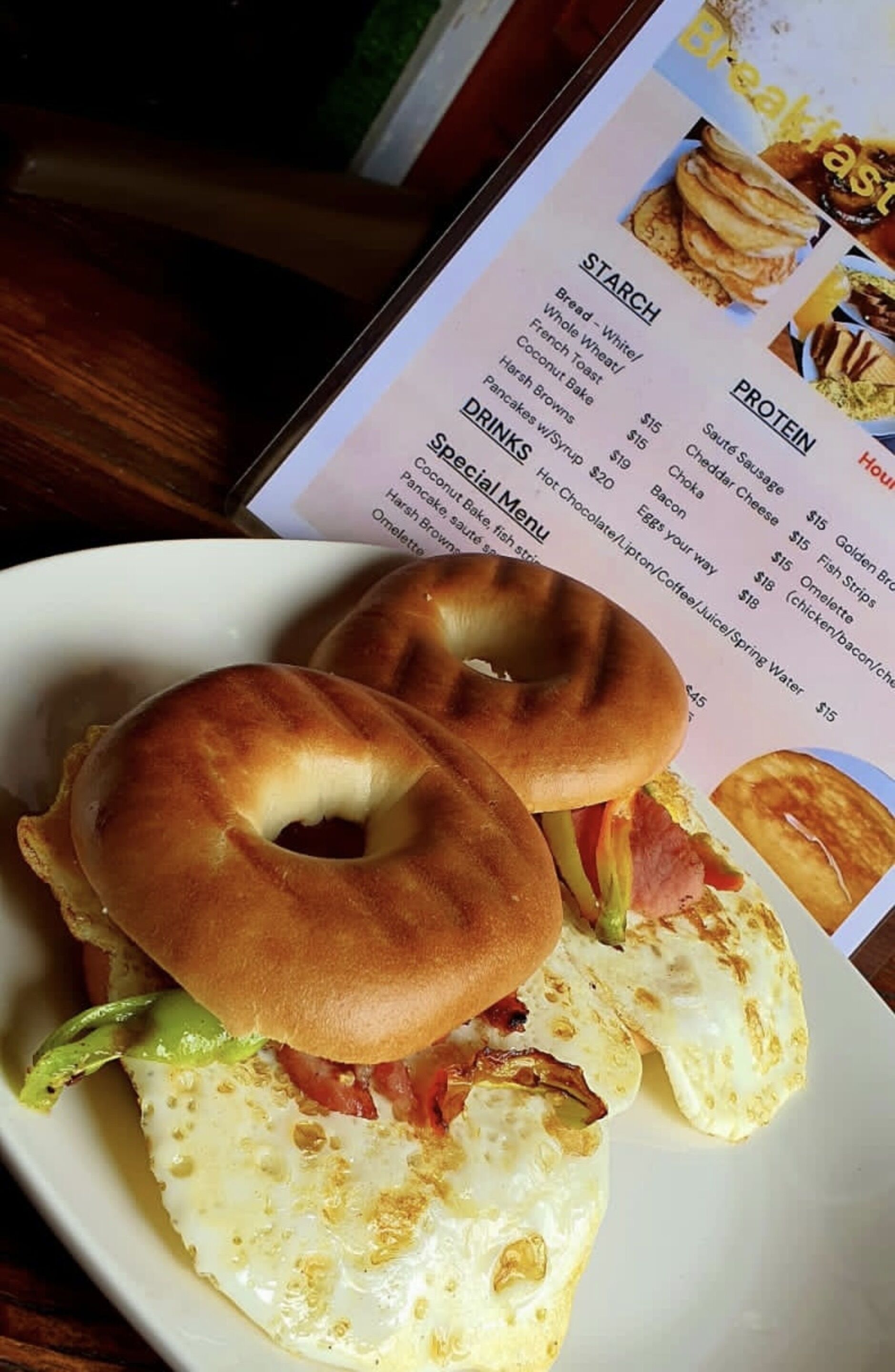 A breakfast plate with a bagel, egg, and bacon.