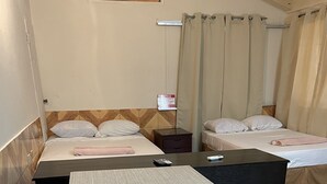 A hotel room with two beds, a small table, a nightstand, and a notice board. - St Ann's Guest House Ltd. (Port of Spain)