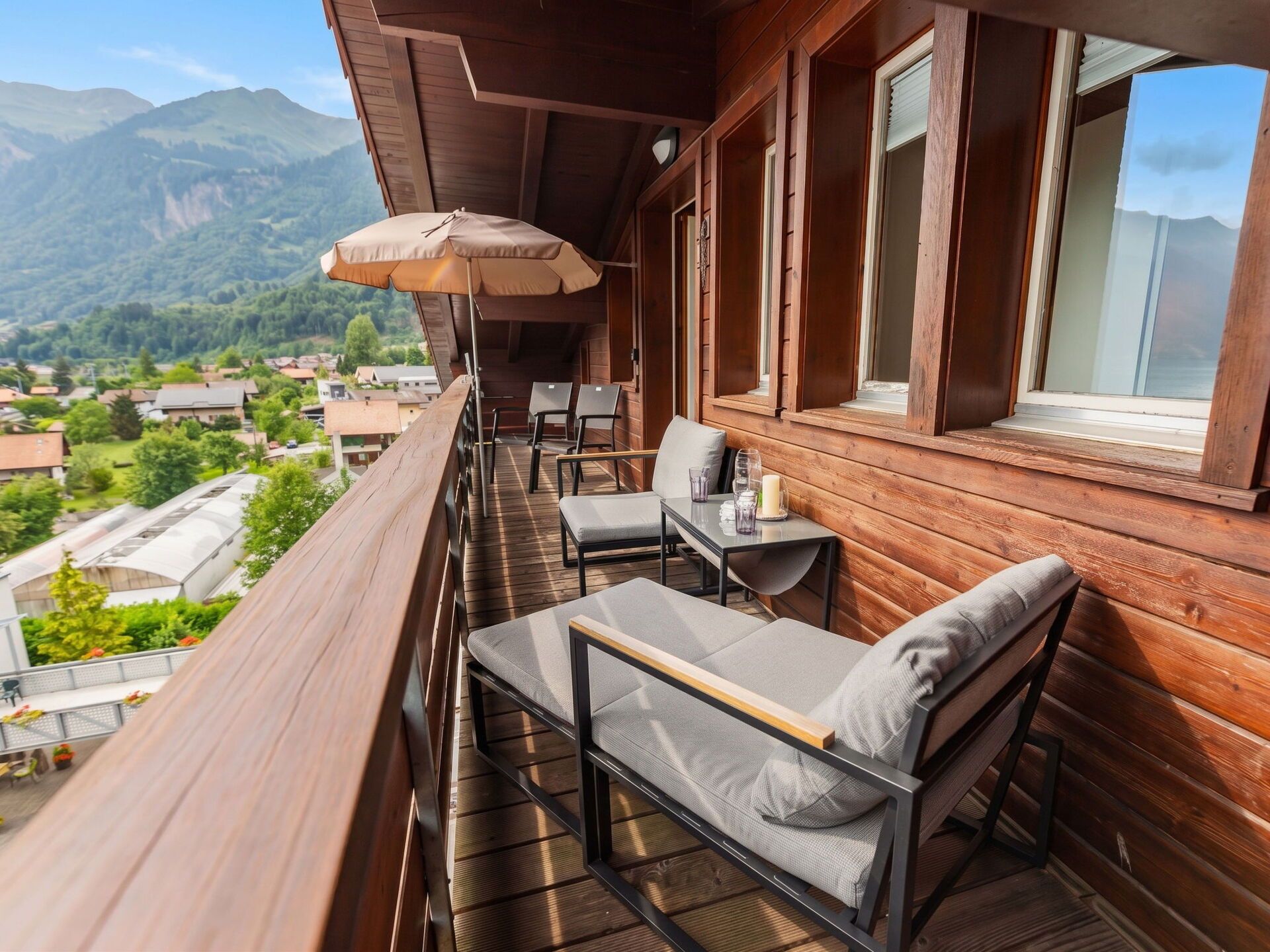 Un balcon avec des balustrades en bois, une table avec des chaises et une vue sur un paysage montagneux.