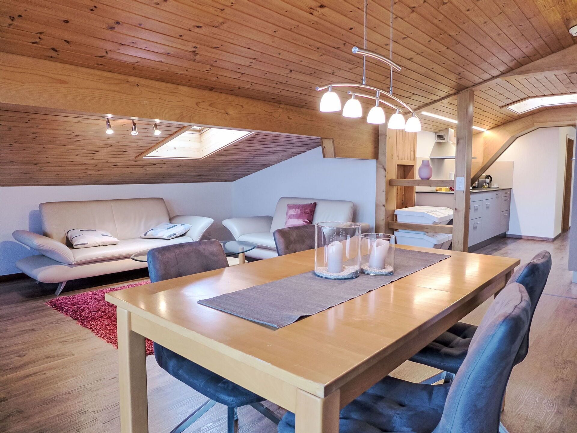 Une pièce confortable de style loft, avec un plafond en bois, une table à manger avec des chaises, un canapé et un coin cuisine.