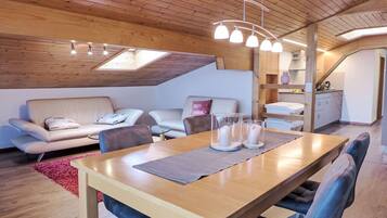 Une pièce confortable de style loft, avec un plafond en bois, une table à manger avec des chaises, un canapé et un coin cuisine.