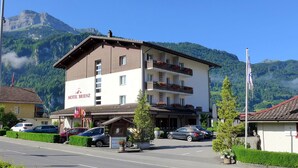 A two-story hotel with balconies, a sign reading "HOTEL BRIENZ," and a mountainous backdrop.