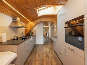 A modern kitchen with wooden ceiling beams, a skylight, and stainless steel appliances. - Beautiful apartment for 4 guests with WIFI, TV and balcony (Kienholz)