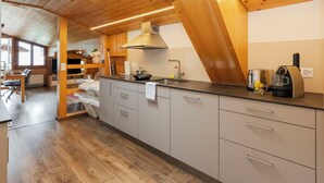 A modern kitchen with a skylight, wooden ceiling, and a coffee machine.