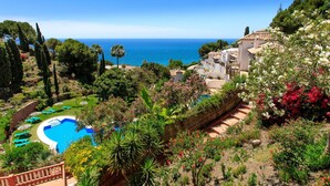 Un resort con piscina, vegetazione rigogliosa e vista sul mare.