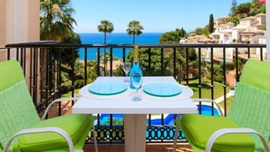 Un balcone con un tavolo apparecchiato per due, con vista sulla costa, palme e case.