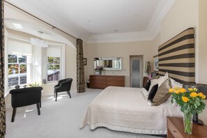 A bedroom with a large bed, a dresser, a chair, and a large mirror.