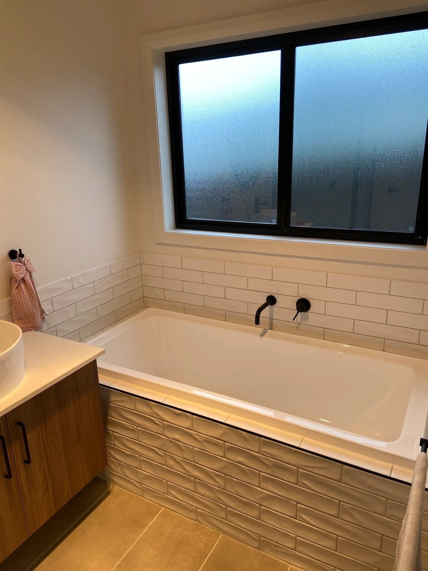 Une salle de bain avec une baignoire, une fenêtre et un porte-serviettes.