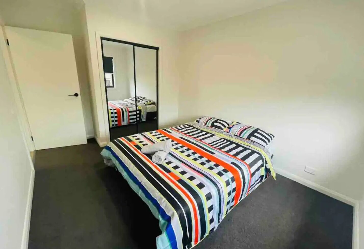 A bedroom with a bed, a mirror, and a door.