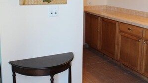 Eine Küche mit Holzschränken, einer Arbeitsplatte, einem Blatt bildendem Gemälde und einem kleinen Tisch.