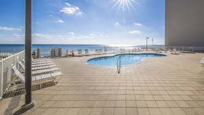 Ein Poolbereich mit Liegestühlen und Blick aufs Meer.