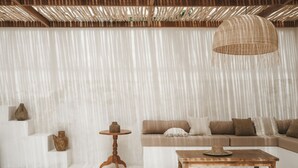 Una sala de estar moderna con un sofá, una mesa de centro de madera y una lámpara colgante de fibras.